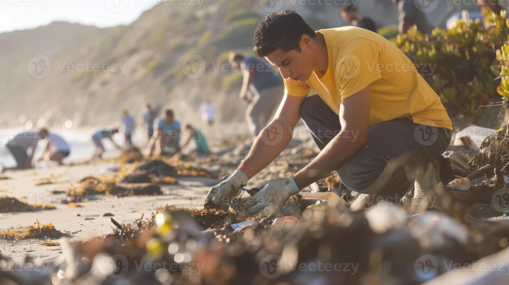 A man helping to clean up a local beach with a team of volunteers picking up trash and debris photo