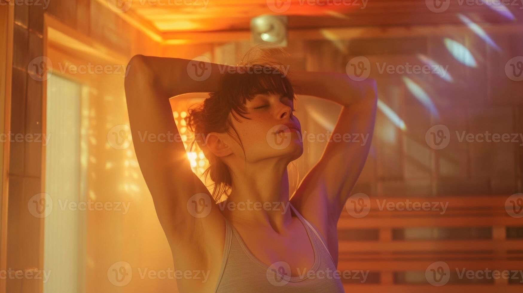 A woman stretches her arms above her head as she enjoys the warmth of the sauna which helps to increase circulation and promote healthy skin. photo