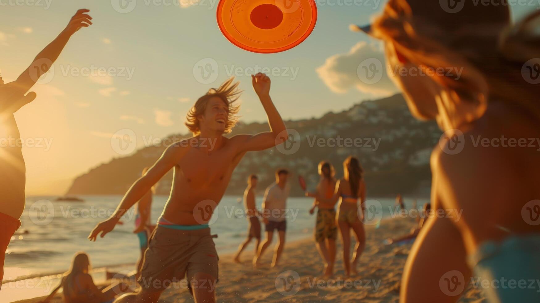 Friends playing a game of frisbee on the beach while waiting for the food to be prepared photo