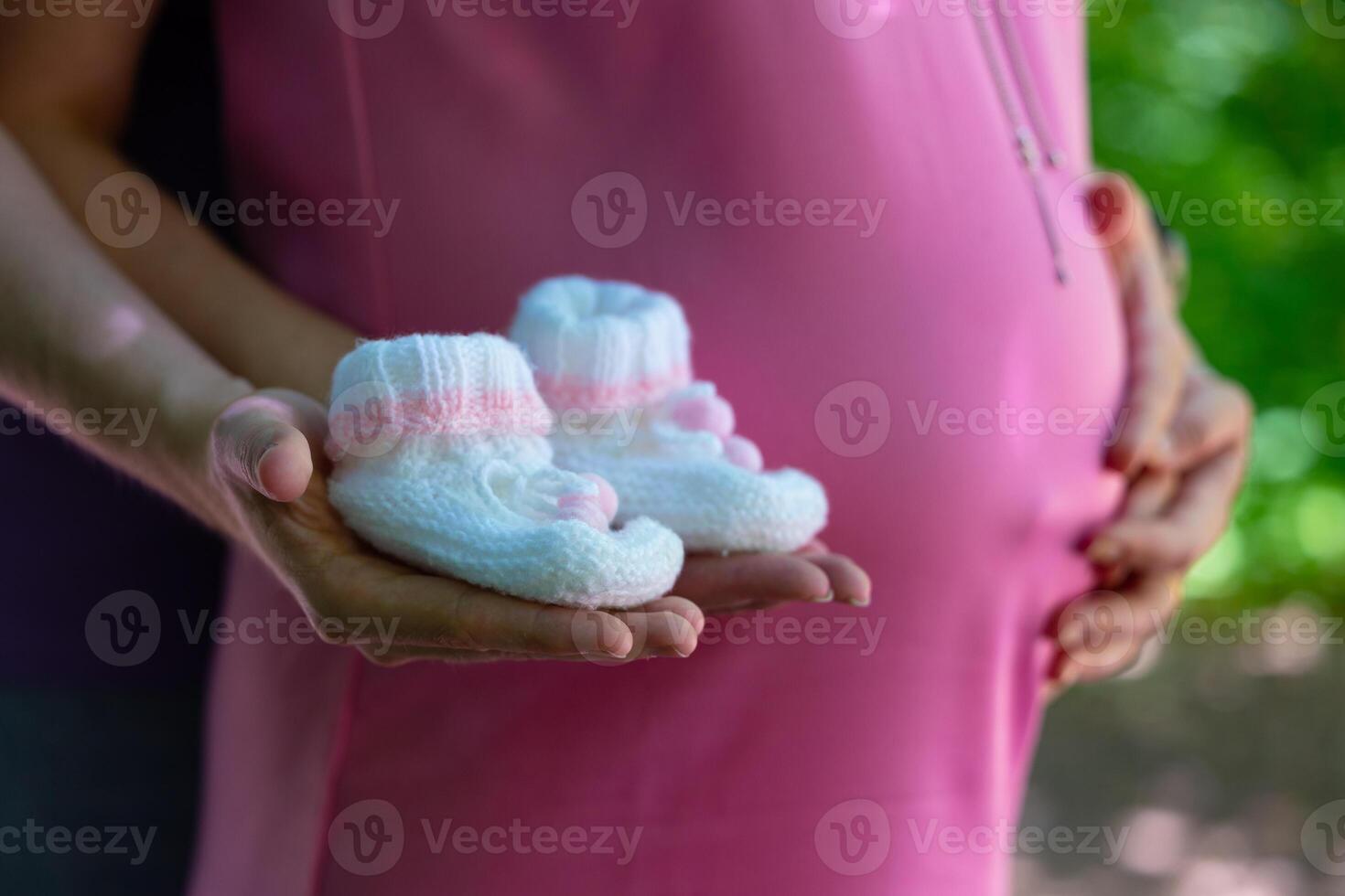 pregnant woman her partner holding booties background their belly concept pregnancy motherhood preparation expectation photo