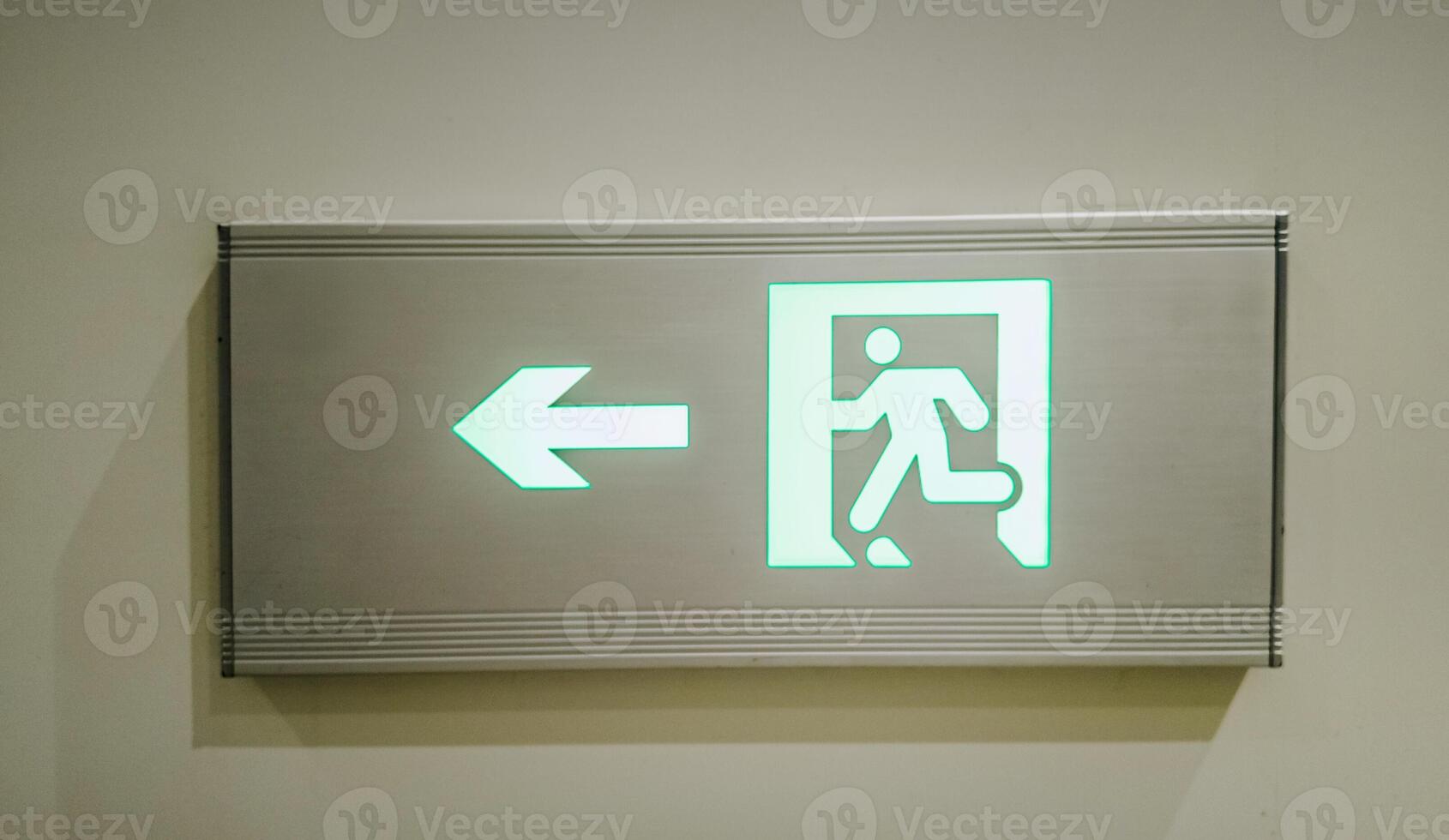 Illuminated green exit sign with running figure and arrow indicating direction, concept related to emergency evacuation and safety protocols photo