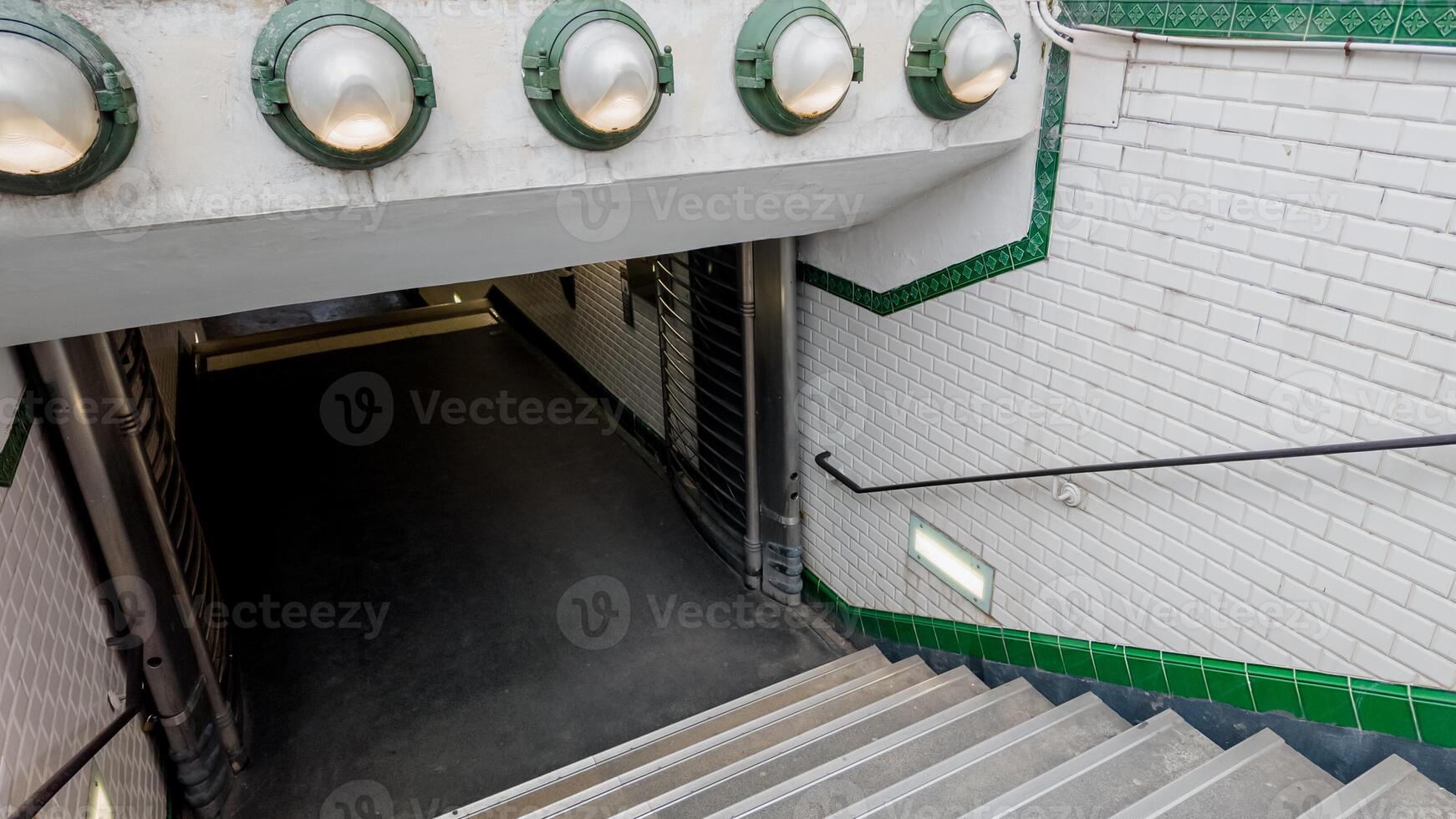 Empty metro station staircase with industrial style lighting and white tiled walls, depicting urban transportation and modern architecture photo