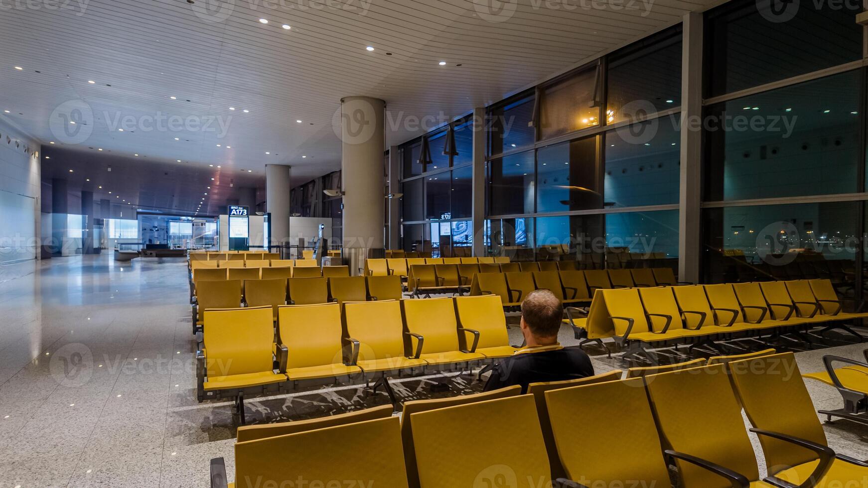 Lone traveler sitting in an empty airport waiting area with yellow seats, symbolizing travel, business trips and holiday commuting, suitable for topics on transportation and solitude photo