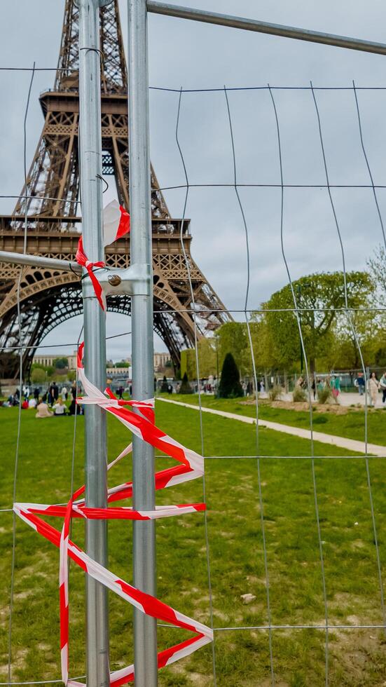 A barrier with red and white tape in front of the Eiffel Tower in Paris, symbolizing restricted access, photographed on April 14th, 2024, during springtime photo