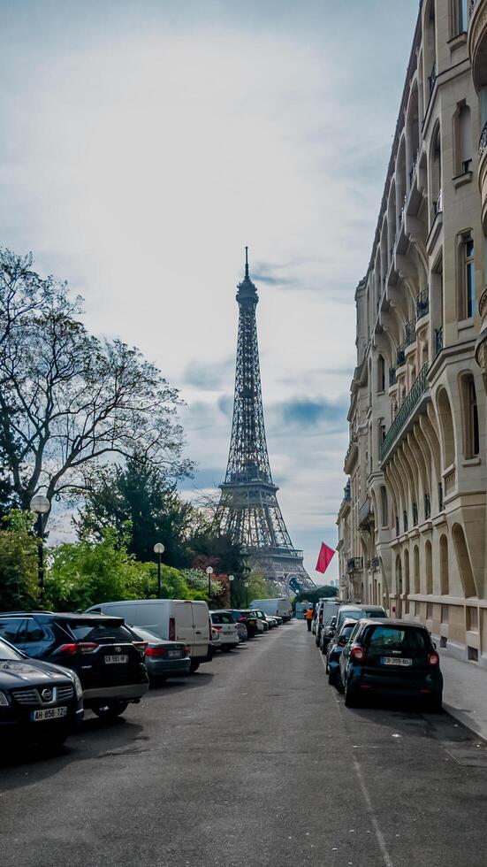 Stunning view of the Eiffel Tower from a Parisian street lined with parked cars, Paris, France, captured on April 14th, 2024, ideal for travel and landmarks photo
