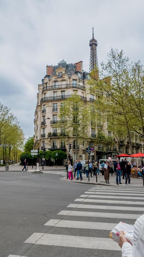 Parisian street scene with diverse pedestrians near Eiffel Tower on a cloudy spring day, perfect for travel and culture themes, Paris, France, April 14, 2024 photo