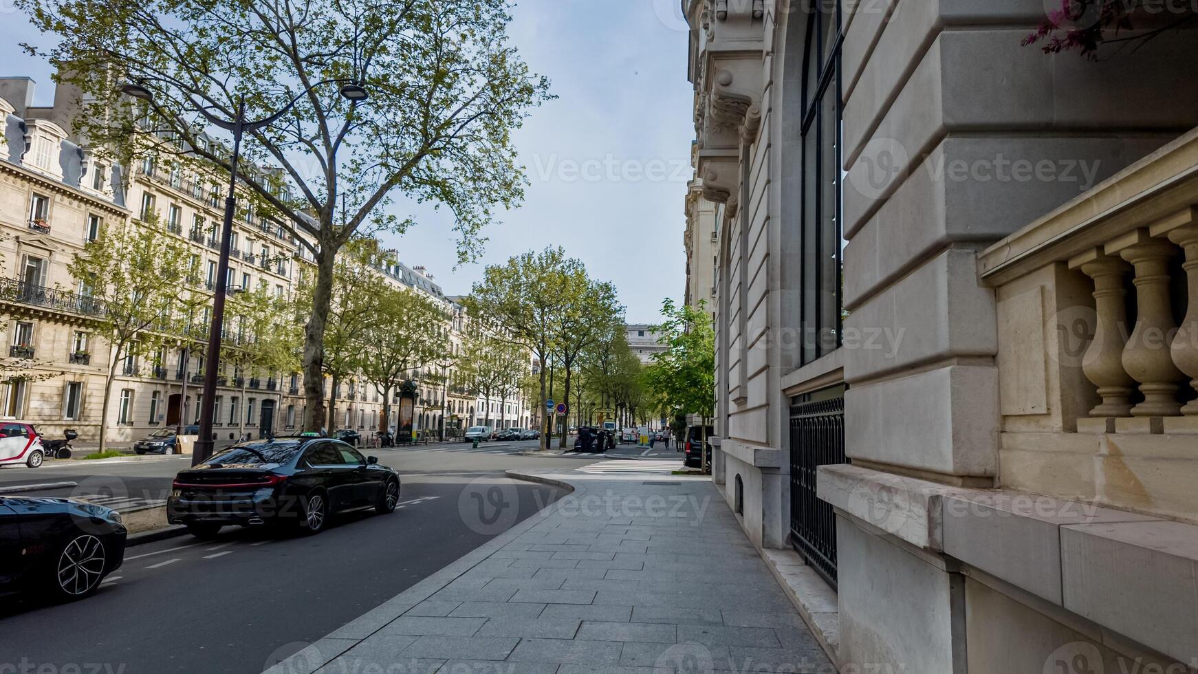 Sunny day on a classic European city street with green trees and historic architecture, ideal for travel and urban lifestyle concepts photo