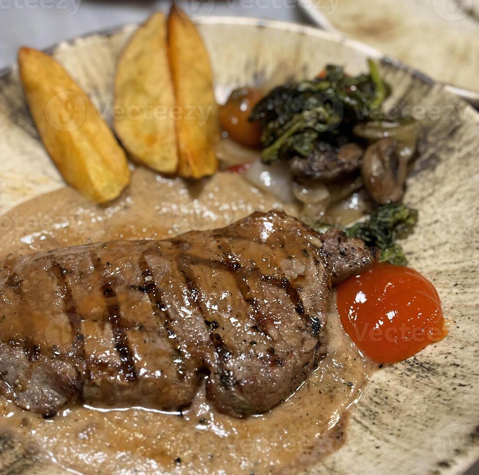 solomillo filete A la parrilla medio raro servido con patatas y ensalada con seta negro pimienta salsa en un restaurante foto