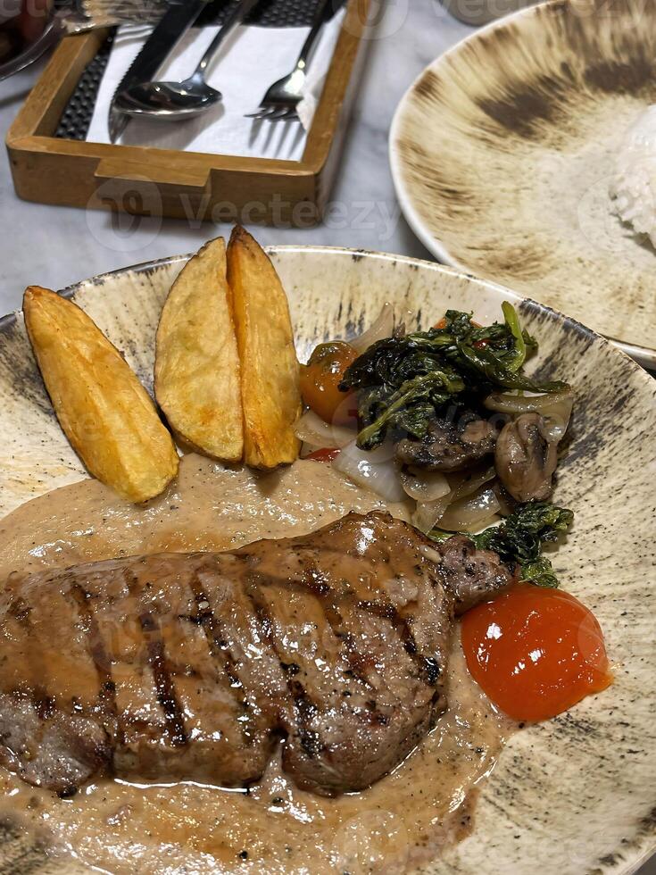 solomillo filete A la parrilla medio raro servido con patatas y ensalada con seta negro pimienta salsa en un restaurante foto