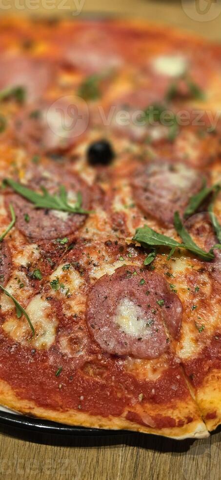 Freshly baked New York style pizza with melted mozzarella cheese and base tomato sauce with lots of pepperoni photo