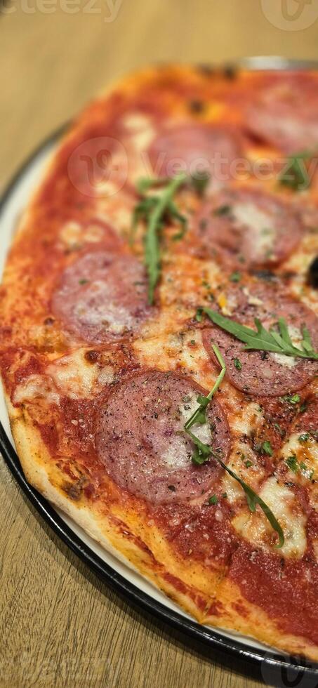 Freshly baked New York style pizza with melted mozzarella cheese and base tomato sauce with lots of pepperoni photo