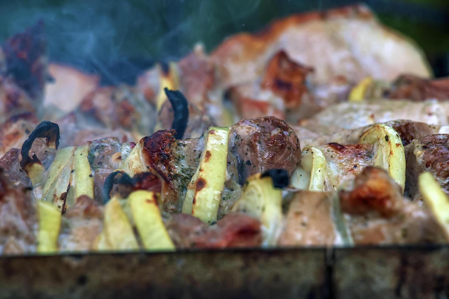 Cooking kebabs on a grill with smoke. Fresh brown BBQ meat cooked on an outdoor grill photo