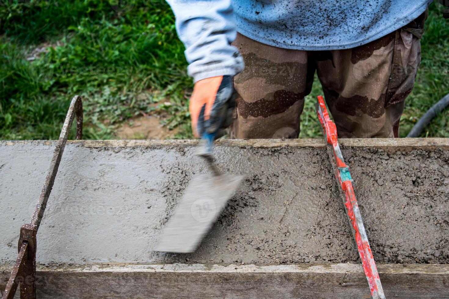 Bricklayer spreading concrete with a trowel and level to build a wall at a construction site photo