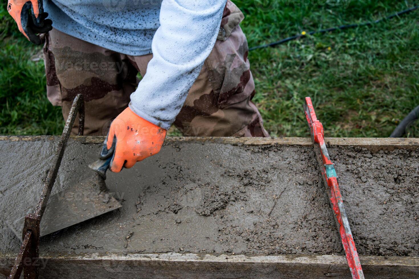 Bricklayer spreading concrete with a trowel and level to build a wall at a construction site photo