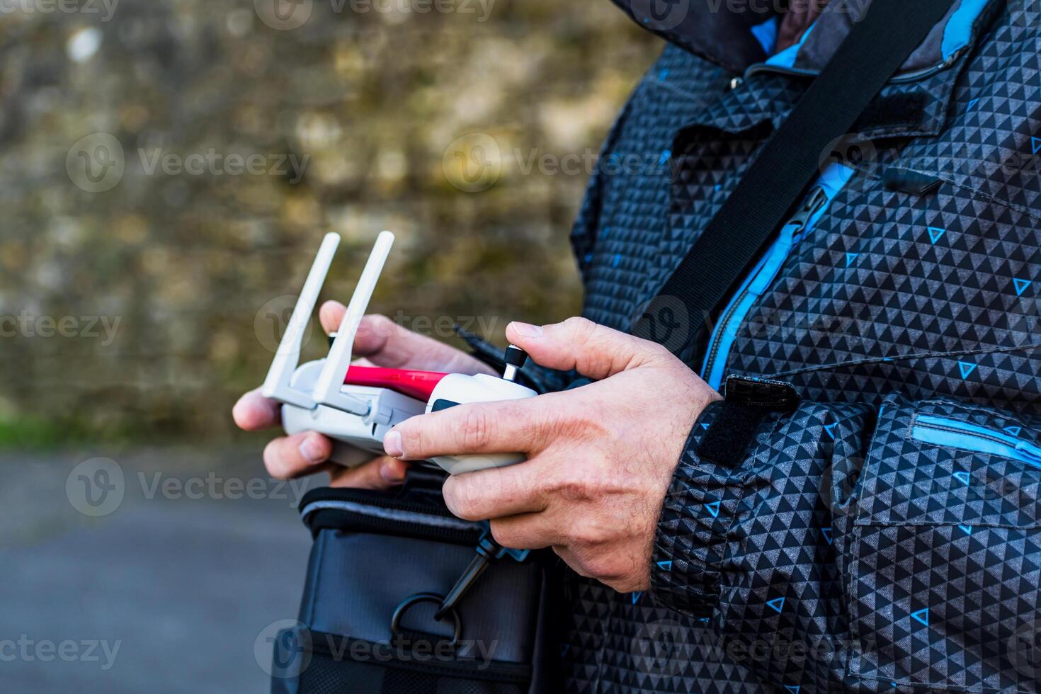 Man piloting a drone using a controller equipped with a joystick and a mobile screen photo