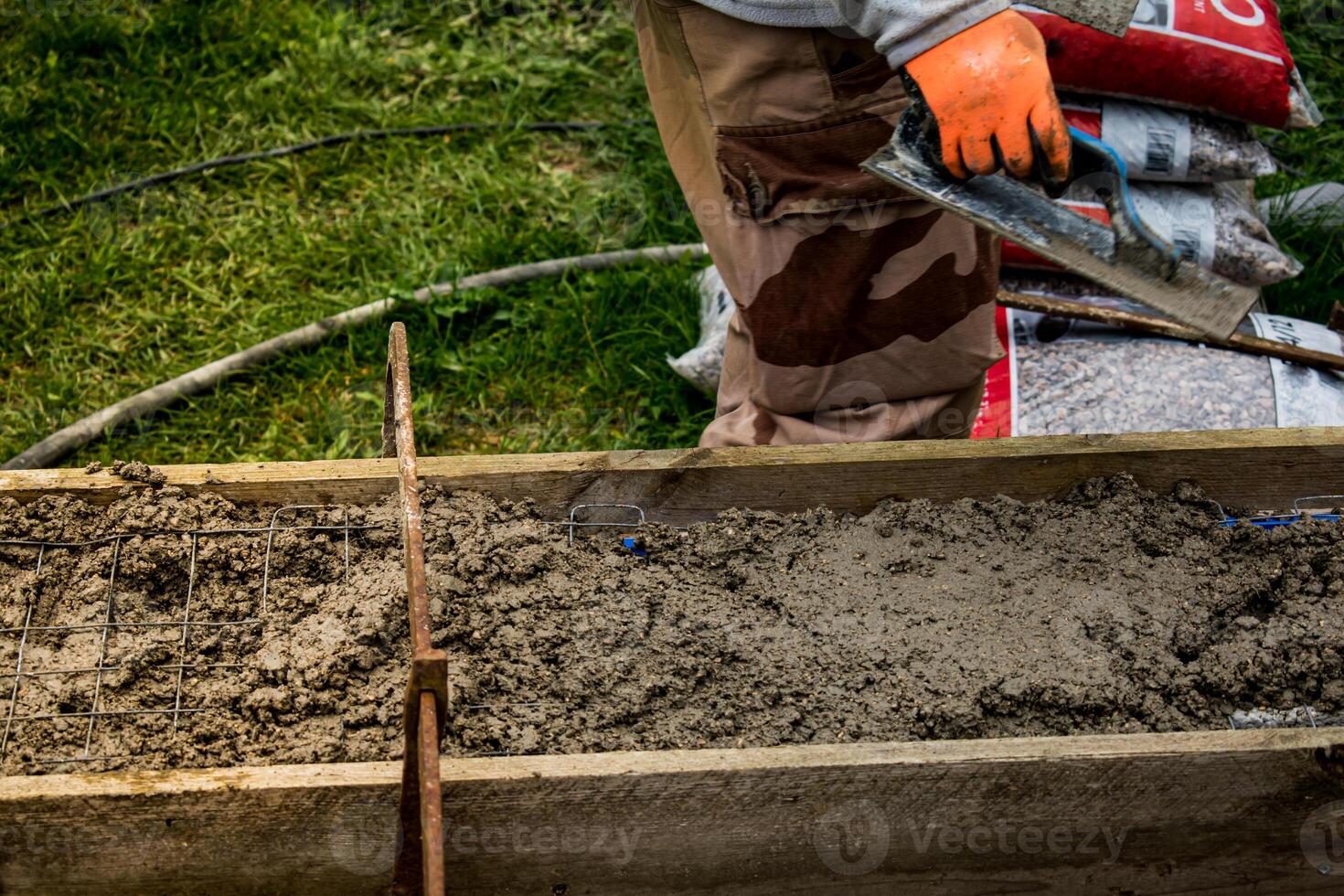 Bricklayer spreading concrete with a trowel and level to build a wall at a construction site photo