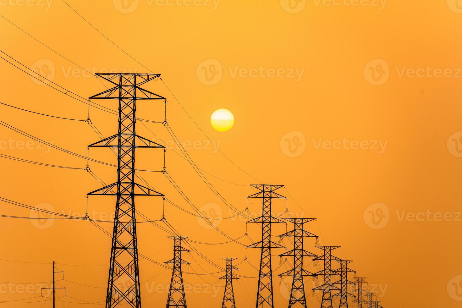 Electricity pillars against a colorful yellow sunset. Silhouette high voltage electric towers, power lines. photo