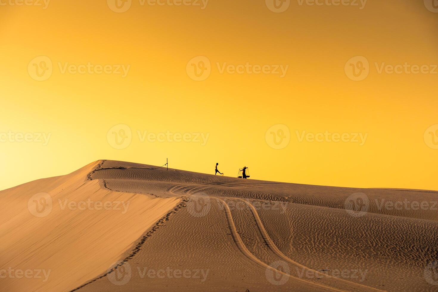 Aerial view of a peasant woman carries a bamboo frame on the shoulder across sand dunes in Ninh Thuan province, Vietnam. It is one of the most beautiful places in Vietnam photo