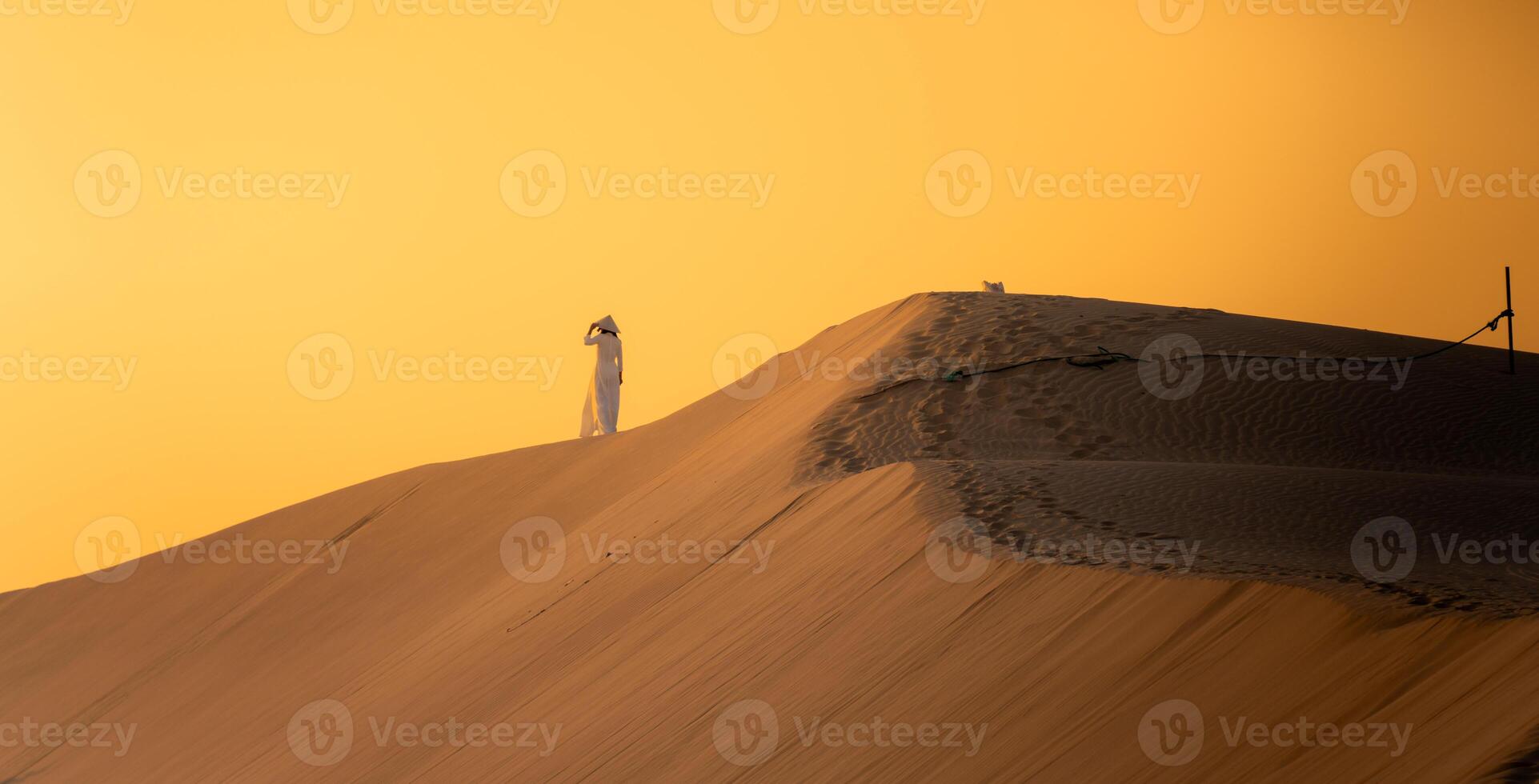 Aerial view of Vietnamese woman wearing ao dai dress across sand dunes in Ninh Thuan province, Vietnam. It is one of the most beautiful places in Vietnam photo