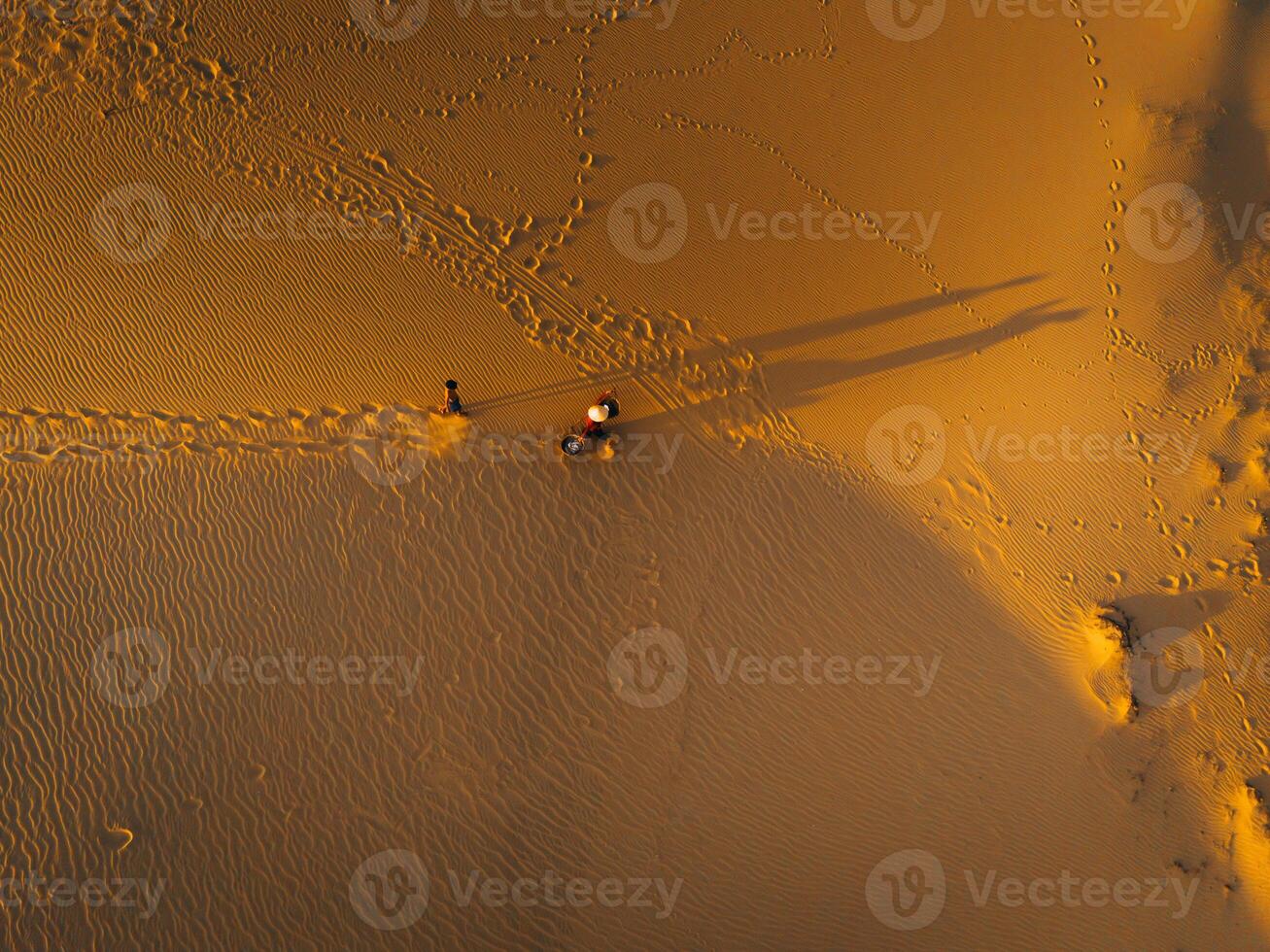 Aerial view of a peasant woman carries a bamboo frame on the shoulder across sand dunes in Ninh Thuan province, Vietnam. It is one of the most beautiful places in Vietnam photo