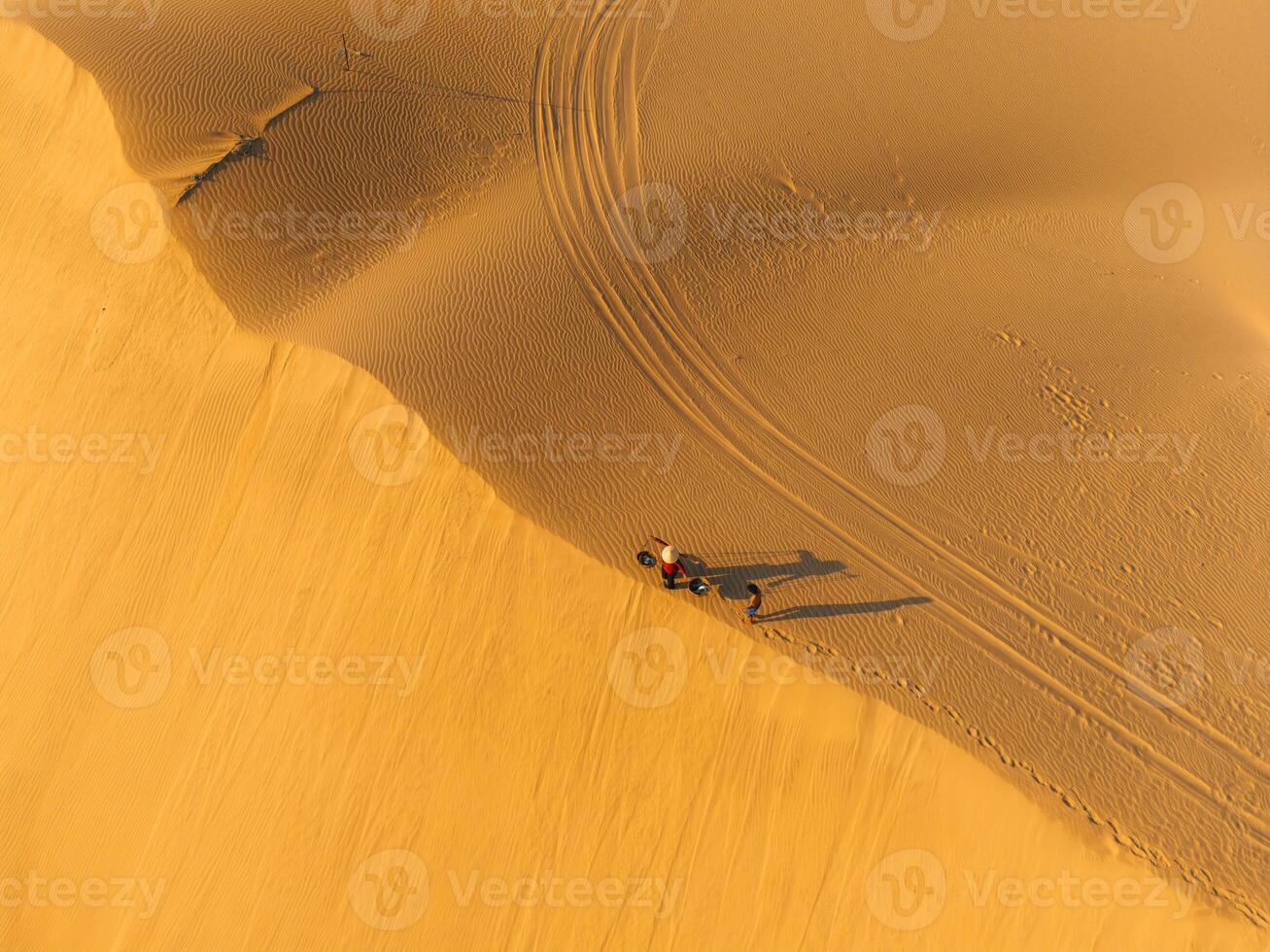 Aerial view of a peasant woman carries a bamboo frame on the shoulder across sand dunes in Ninh Thuan province, Vietnam. It is one of the most beautiful places in Vietnam photo