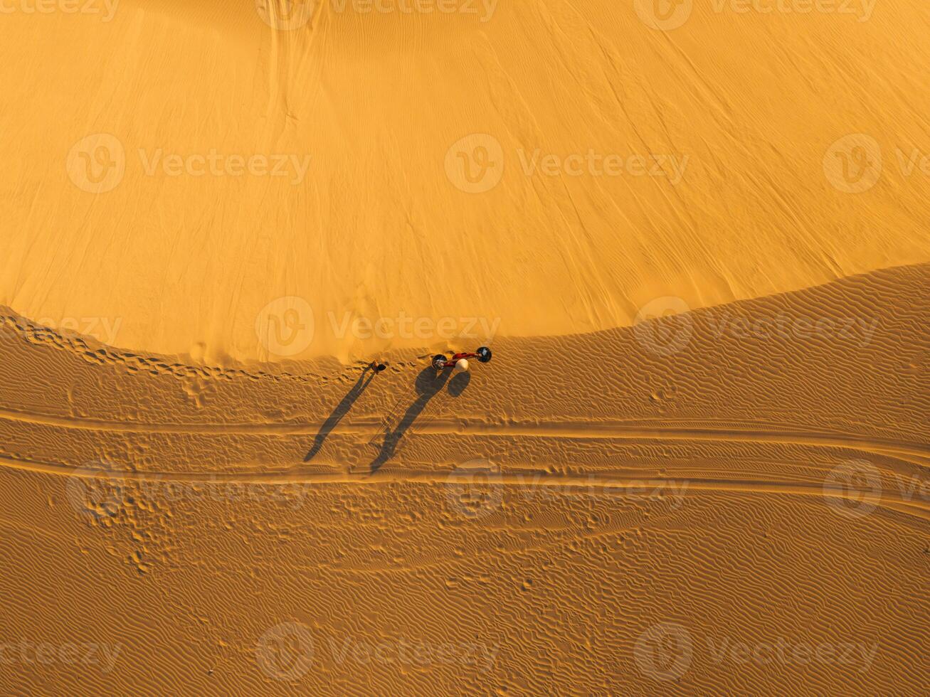 Aerial view of a peasant woman carries a bamboo frame on the shoulder across sand dunes in Ninh Thuan province, Vietnam. It is one of the most beautiful places in Vietnam photo
