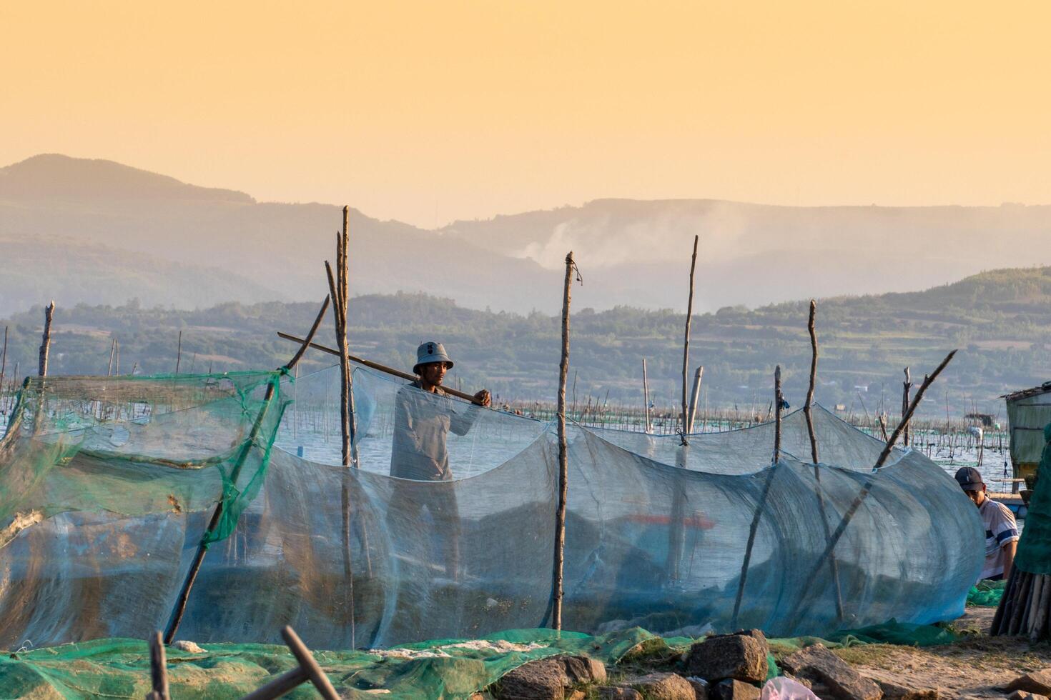 Traditional fishermen and boats in O Loan lagoon during sunset, Phu Yen province, Vietnam. Travel and landscape concept photo