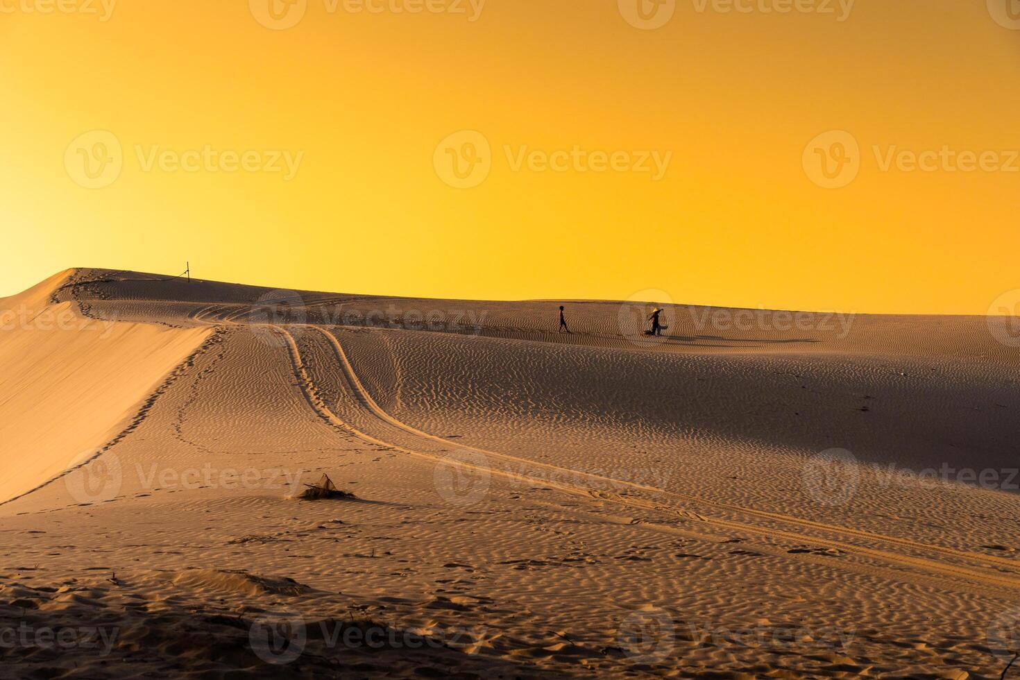 Aerial view of a peasant woman carries a bamboo frame on the shoulder across sand dunes in Ninh Thuan province, Vietnam. It is one of the most beautiful places in Vietnam photo
