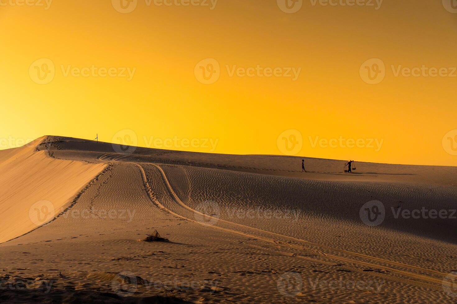 Aerial view of a peasant woman carries a bamboo frame on the shoulder across sand dunes in Ninh Thuan province, Vietnam. It is one of the most beautiful places in Vietnam photo