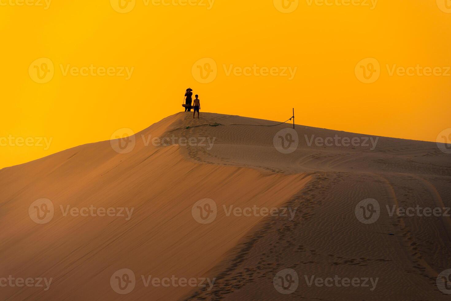 Aerial view of a peasant woman carries a bamboo frame on the shoulder across sand dunes in Ninh Thuan province, Vietnam. It is one of the most beautiful places in Vietnam photo