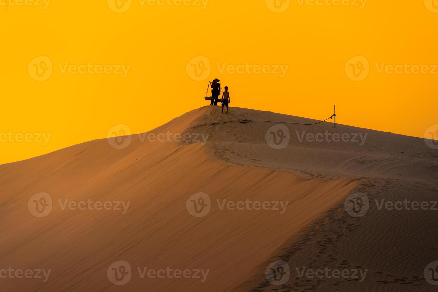 Aerial view of a peasant woman carries a bamboo frame on the shoulder across sand dunes in Ninh Thuan province, Vietnam. It is one of the most beautiful places in Vietnam photo