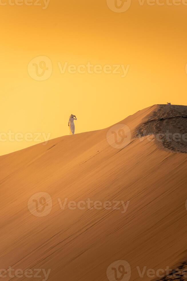 Aerial view of Vietnamese woman wearing ao dai dress across sand dunes in Ninh Thuan province, Vietnam. It is one of the most beautiful places in Vietnam photo