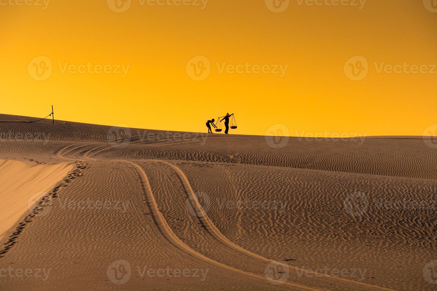 Aerial view of a peasant woman carries a bamboo frame on the shoulder across sand dunes in Ninh Thuan province, Vietnam. It is one of the most beautiful places in Vietnam photo