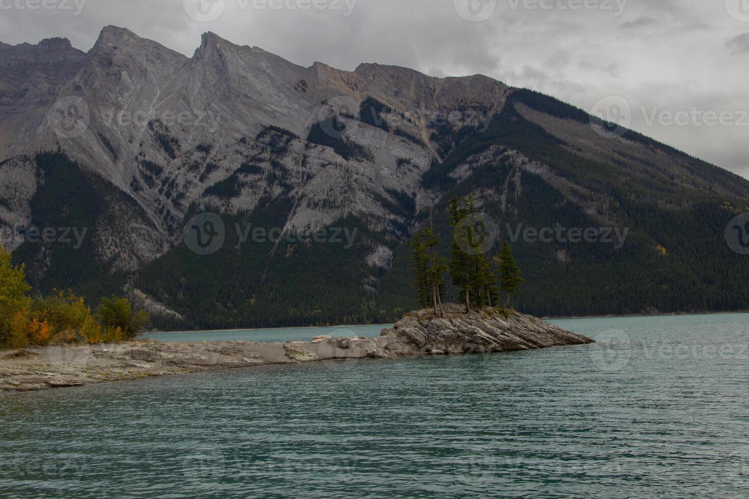 nublado día en rocoso isla en lago minnewanka, canadiense rocoso montañas, banff nacional parque foto