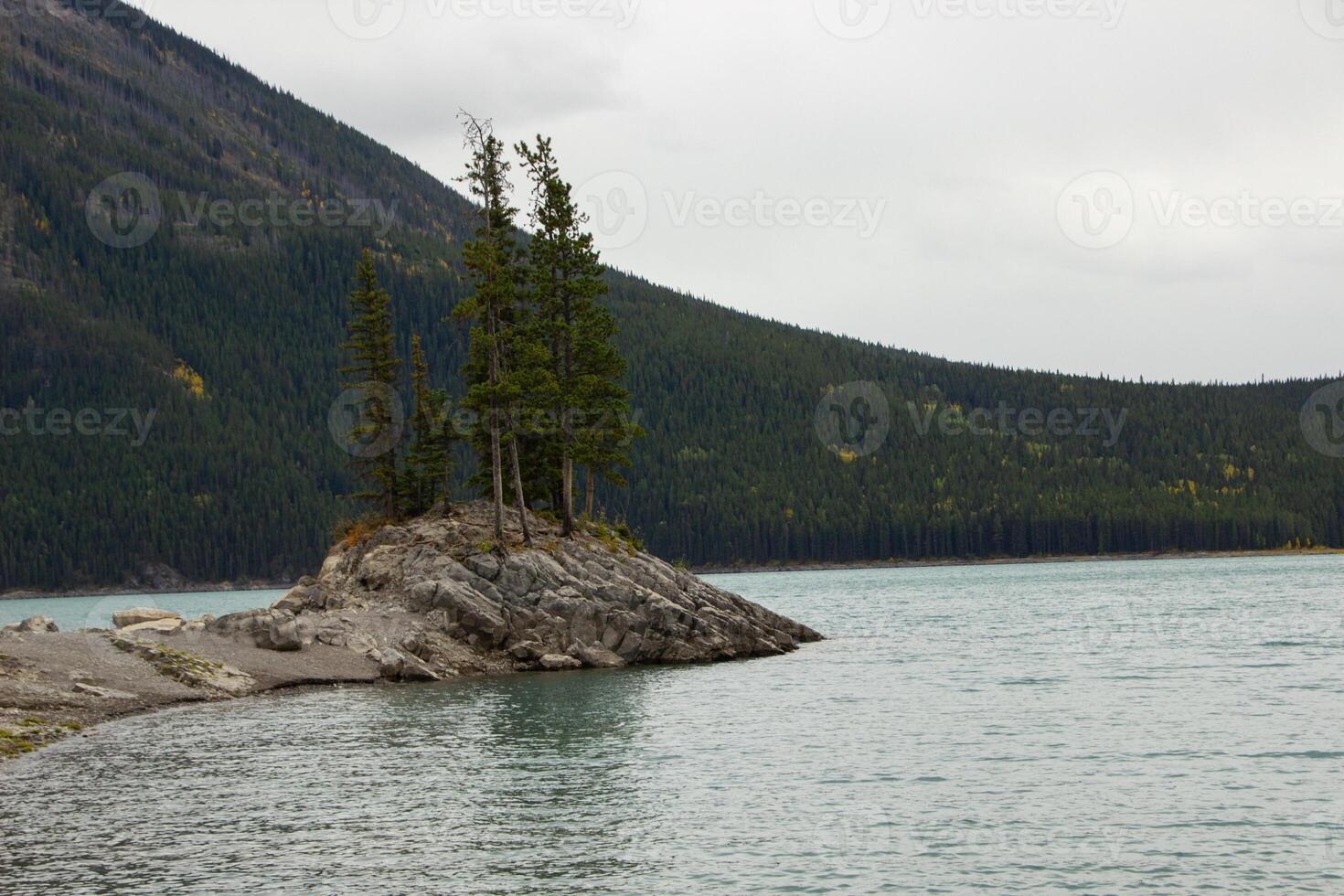 nublado día en rocoso isla en lago minnewanka, canadiense rocoso montañas, banff nacional parque foto