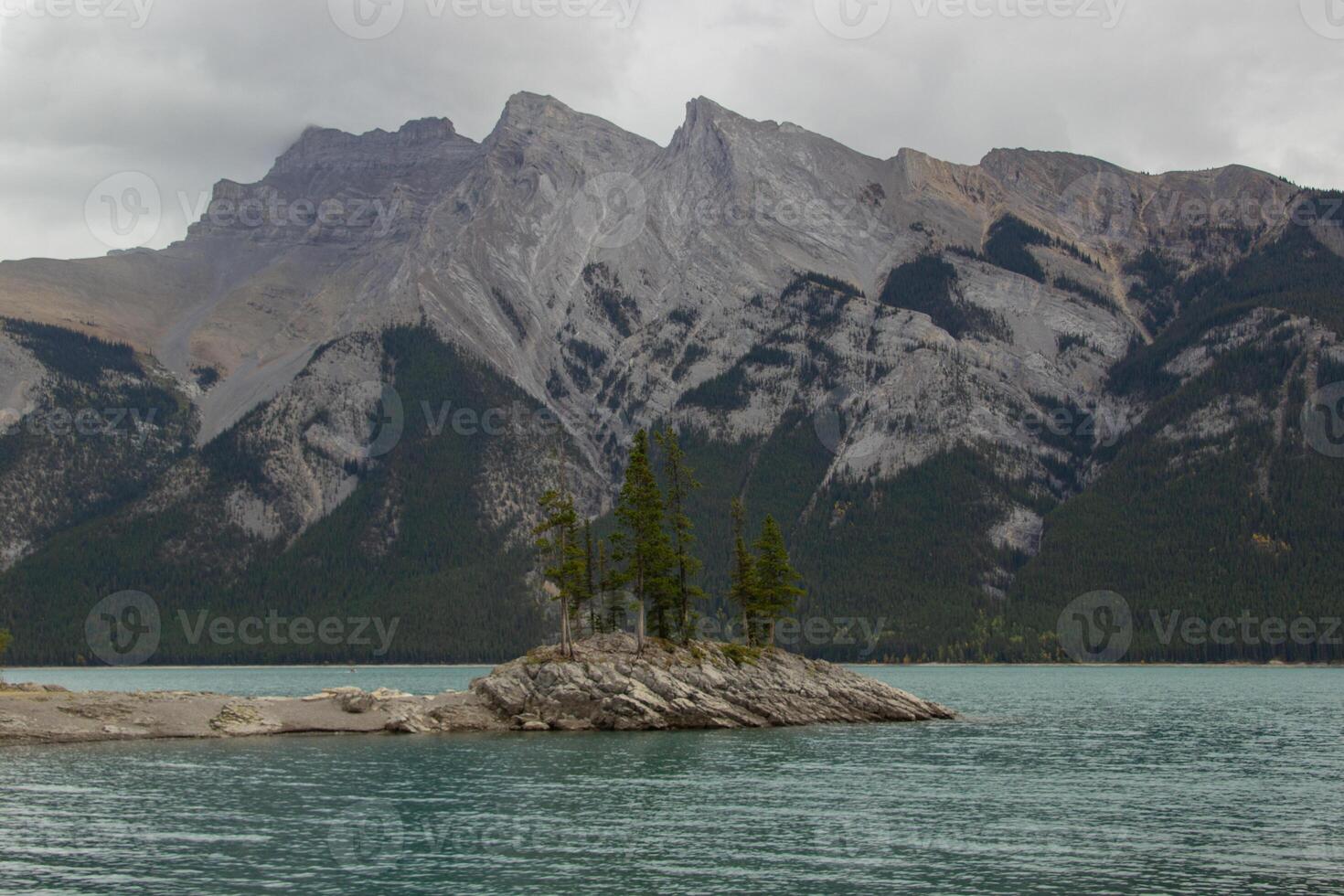 nublado día en rocoso isla en lago minnewanka, canadiense rocoso montañas, banff nacional parque foto