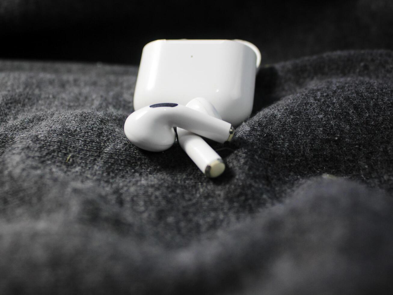Closeup white TWS true wireless stereo earbuds in case isolated on black background. photo