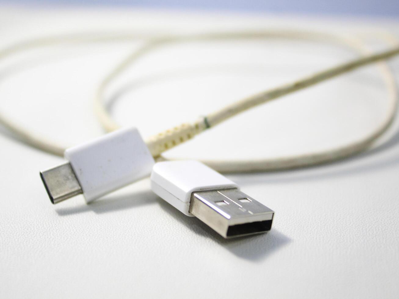 Close up the white broken smartphone usb cable on white wooden background. photo