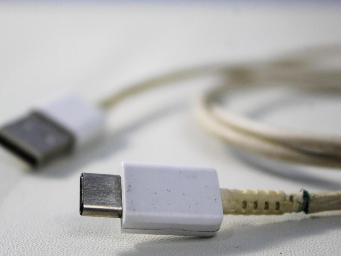 cerca arriba el blanco roto teléfono inteligente USB cable en blanco de madera antecedentes. foto