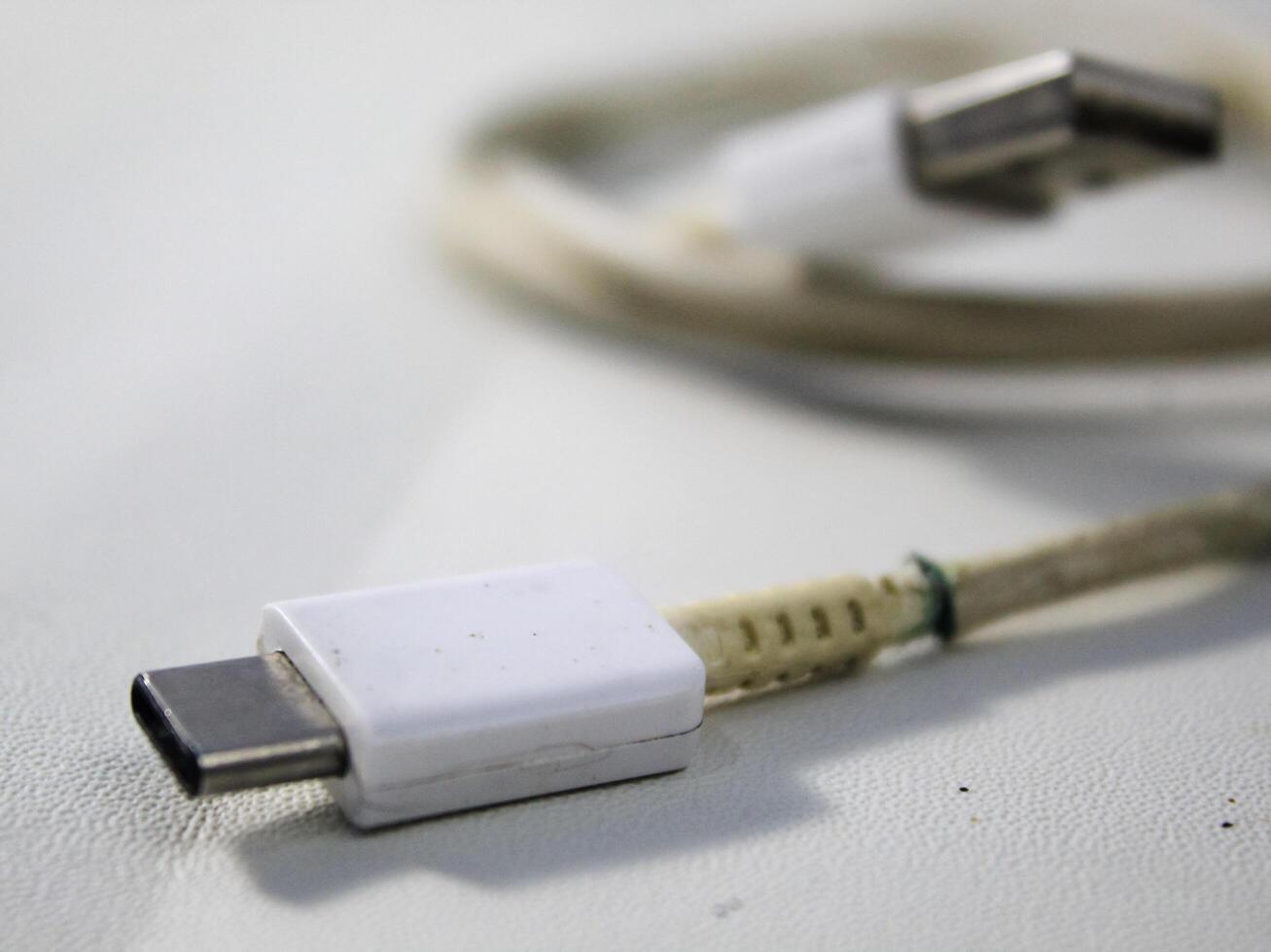 Close up the white broken smartphone usb cable on white wooden background. photo