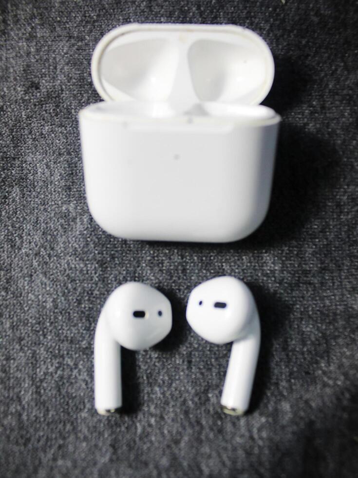 Closeup white TWS true wireless stereo earbuds in case isolated on black background. photo