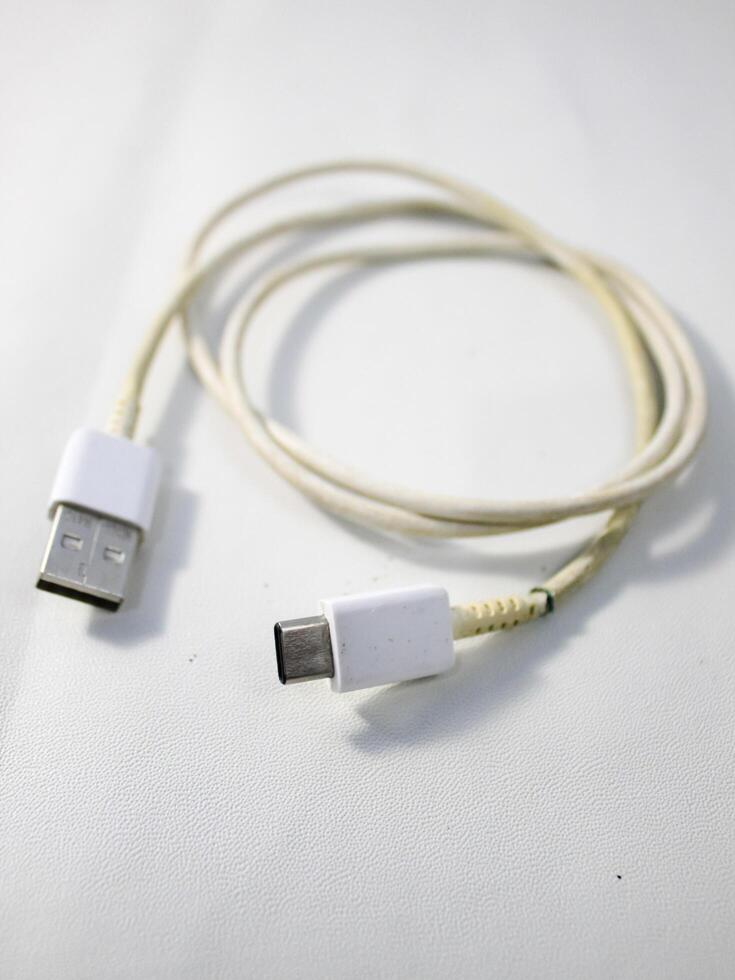 Close up the white broken smartphone usb cable on white wooden background. photo