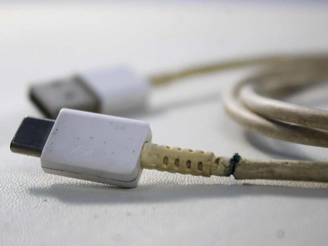 Close up the white broken smartphone usb cable on white wooden background. photo