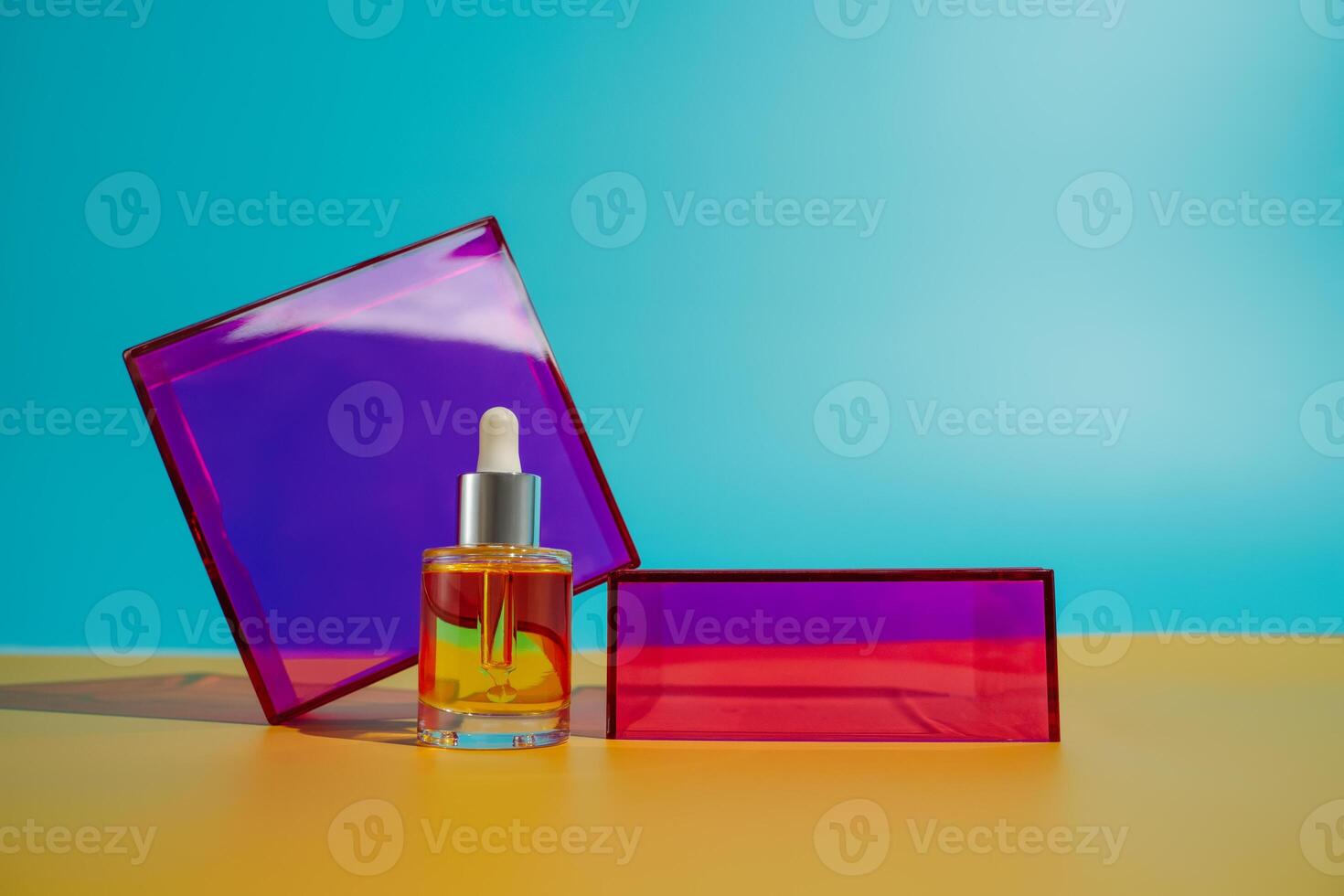 Face oil in glass bottle on yellow and blue background with pink and purple geometric elements photo