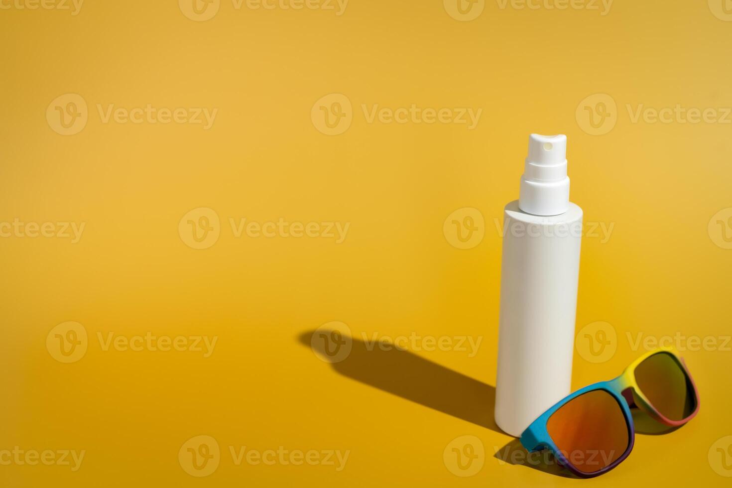 Blank white spray bottle with sunglasses in direct sunlight photo