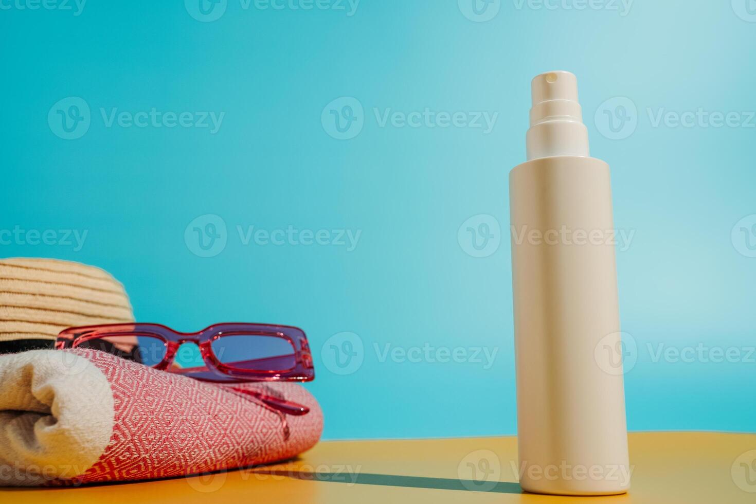 Blank sunscreen bottle sun hat and sunglasses on beach photo