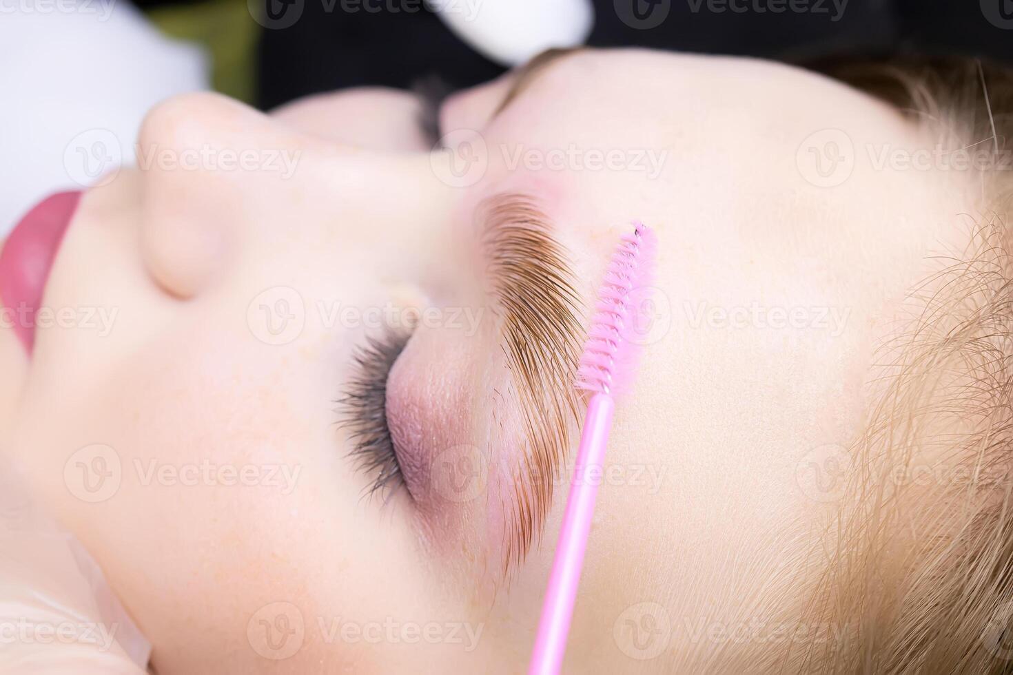 macro photography of the eye, the eyebrow of which is combined with a brush, the hairs are laid after the laminating composition photo