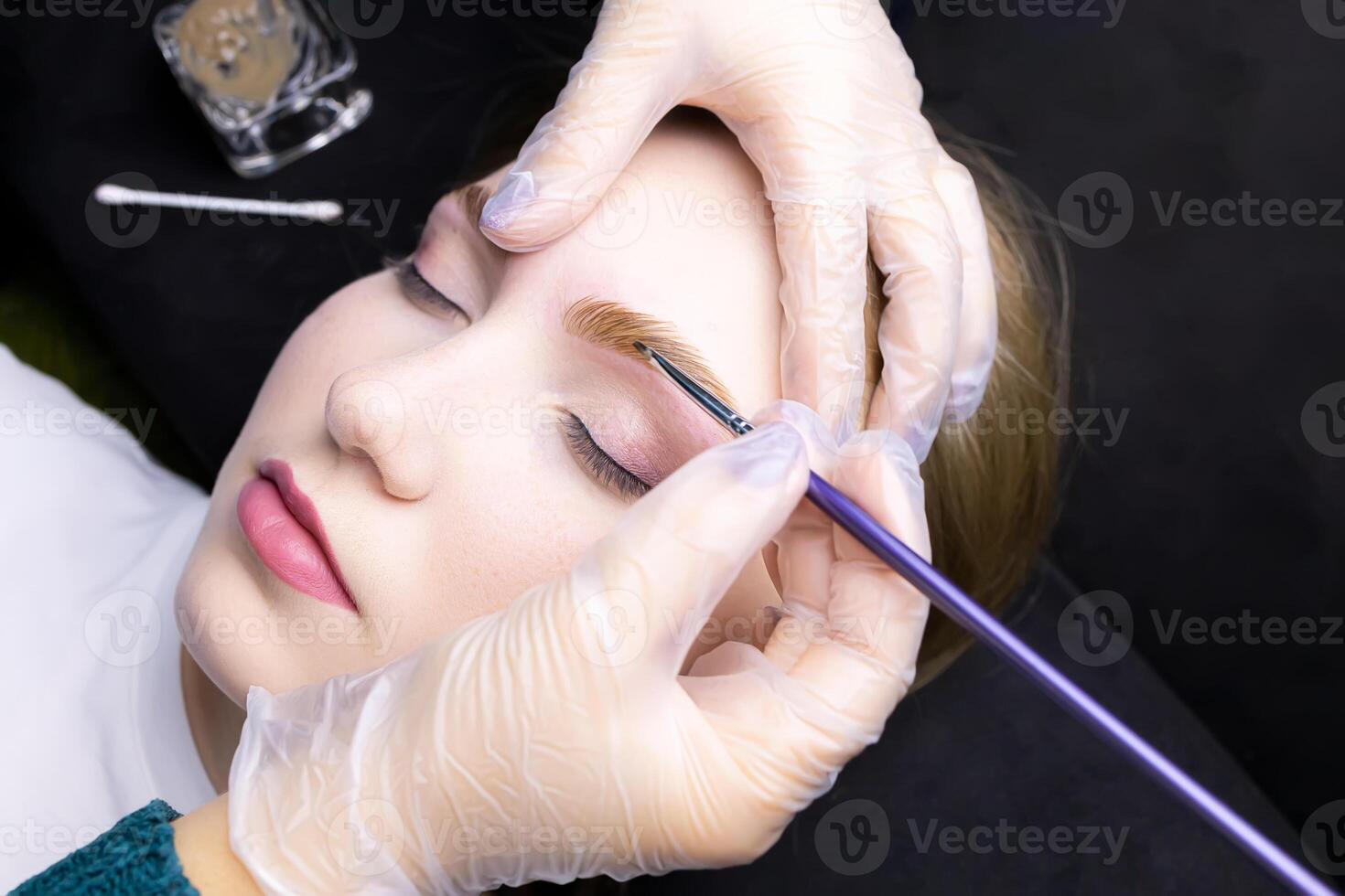 applying paint to the model's eyebrows with a brush after lamination photo