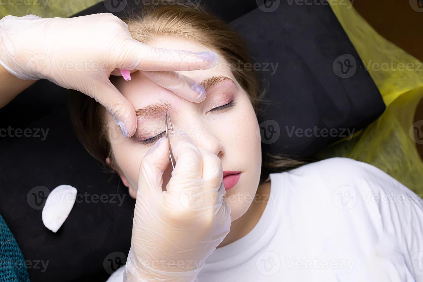 the hands of the master adjust the combed eyebrows up after lamination with compositions photo