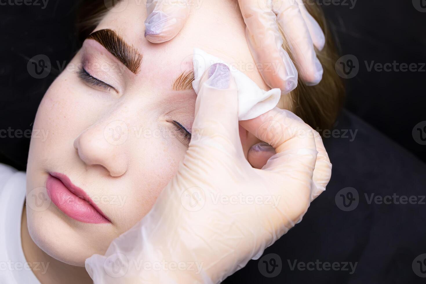 in the hands of the master is a cotton sponge with which he removes the remnants of paint from painted eyebrows photo